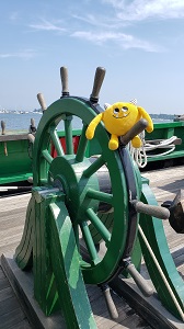 Yellow stuffed book monster at the wheel of a boat