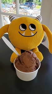 Yellow stuffed monster eating a bowl of ice cream