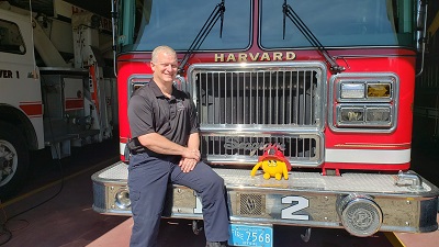 Yellow stuffed animal monster on a fire truck with fire chief