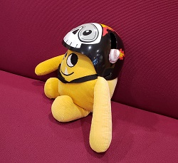 Photo of a yellow stuffed animal monster in a bike helmet