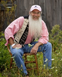 Photo of a man with a long beard wearing a pink shirt multicolored vest and blue jeans