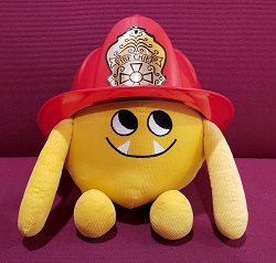 Photo of a yellow stuffed animal monster in a firefighter's helmet