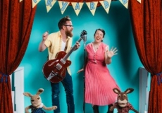 Photo of a man with a guitar and a woman singing into a microphone