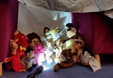 Photo of a group of stuffed animals sitting around a camp lantern