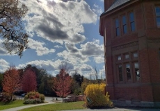 Photo of a brick library building against a blue sky with sun and clouds