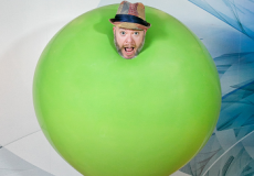 Photo of a man's head coming out of a giant green balloon