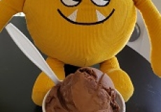 Yellow stuffed monster eating a bowl of ice cream