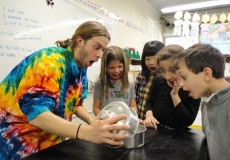 Photo of a teacher showing four children an exciting science experiment