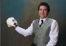 Photo of a man dressed as a magician holding a fake skull