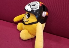 Photo of a yellow stuffed animal monster in a bike helmet