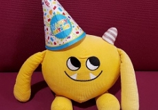 Photo of a yellow stuffed animal monster wearing a birthday hat