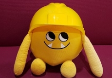 Photo of a yellow stuffed animal monster wearing a construction hat