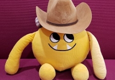 Photo of a yellow stuffed animal monster wearing a cowboy hat