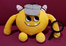 Photo of a yellow stuffed animal monster wearing a detective hat