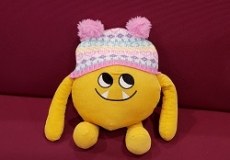 Photo of a yellow stuffed animal monster wearing a winter hat